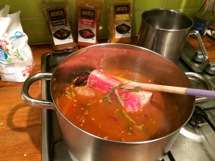Once the beef is browned and the stock has absorbed  the spices, add all the beef stock and tamarind water.  Ensure that all the beef is submerged under the stock.  The bone will not be fully submerged, but whilst its cooking, keep turning the bone to ensure even cooking. Finally add in the curry leaves and allow the beef to cook over a medium fire. 